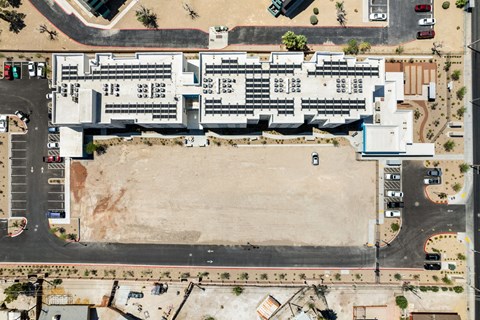 an aerial view of a large white building with a dirt parking lot in front of it